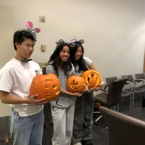 Three lab members holding their jack-o-lanterns